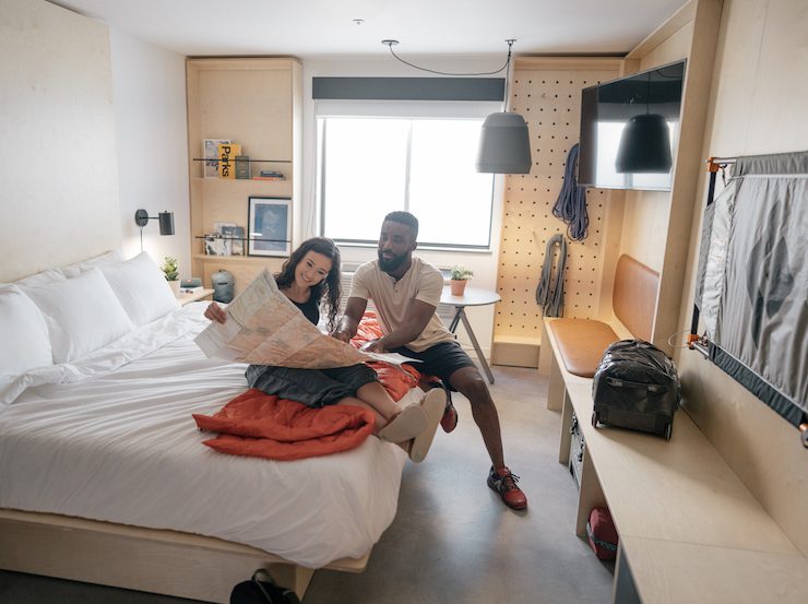 Man and woman looking at a trail map on a large bed inside a camper