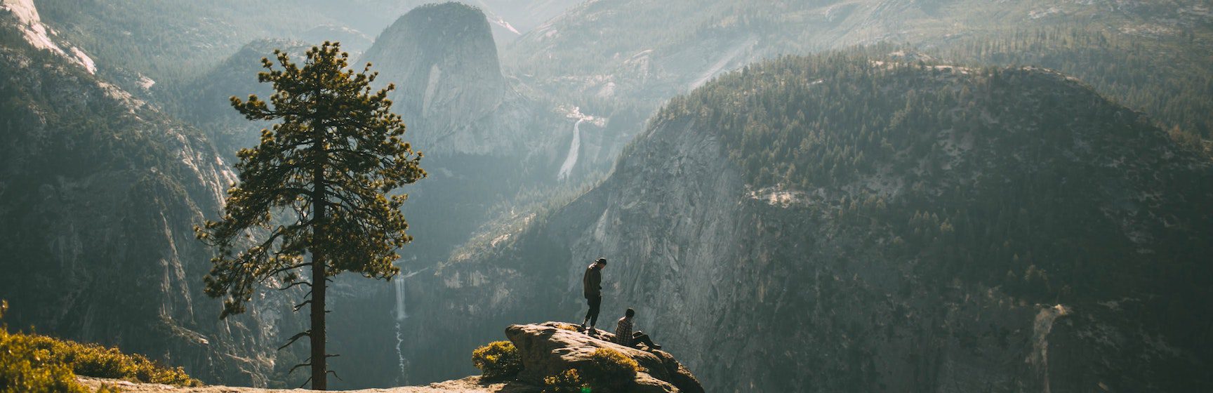 two people sitting on a rock at the top of a mountain