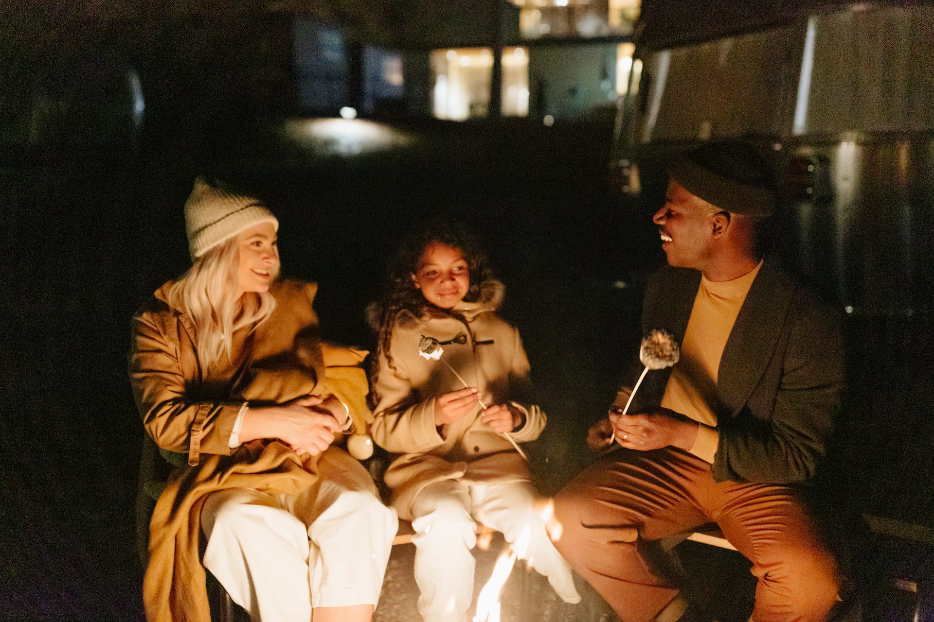 family sitting at a campfire roasting marshmallows
